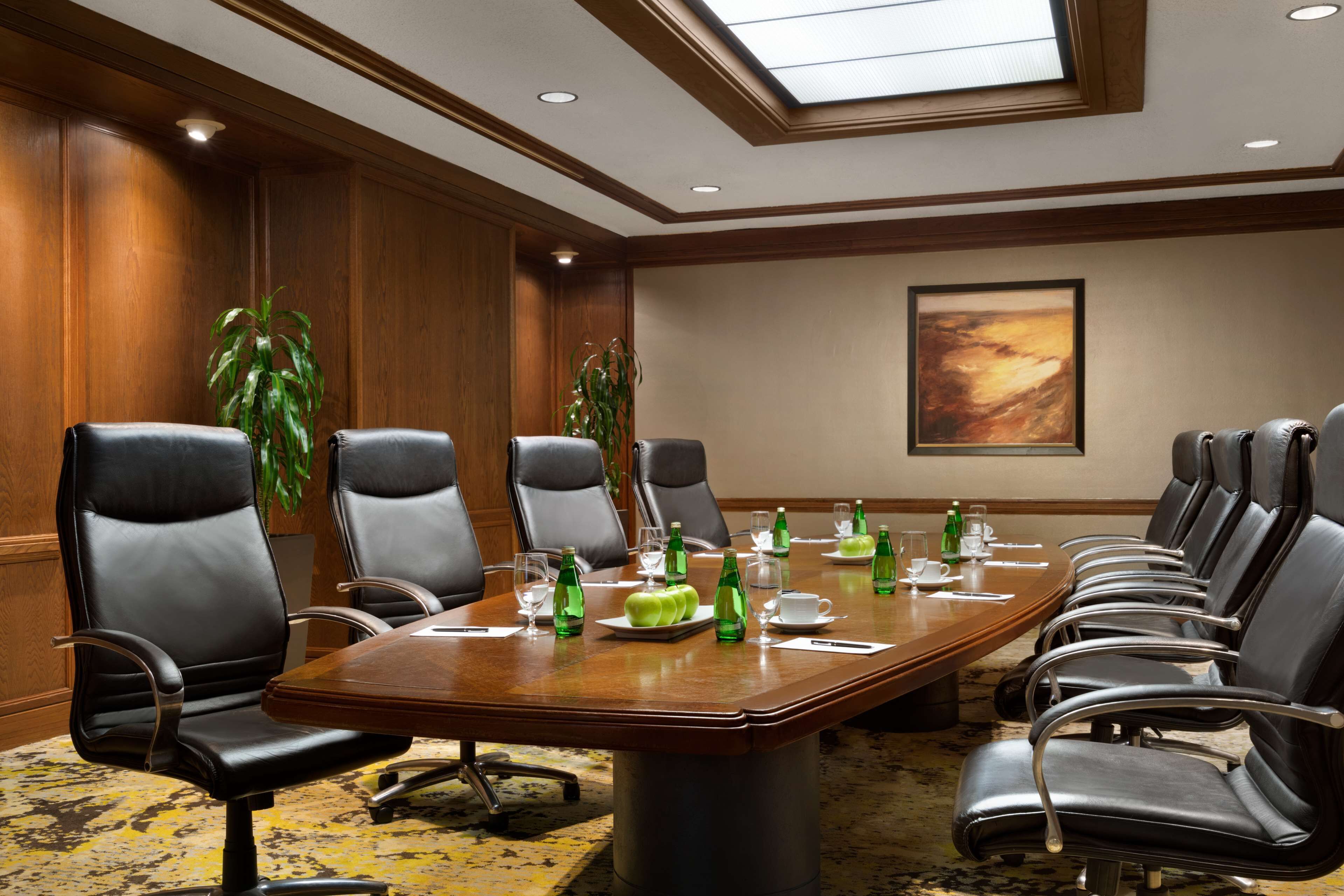 A conference room with a long table, multiple chairs, and green bottles on the table.