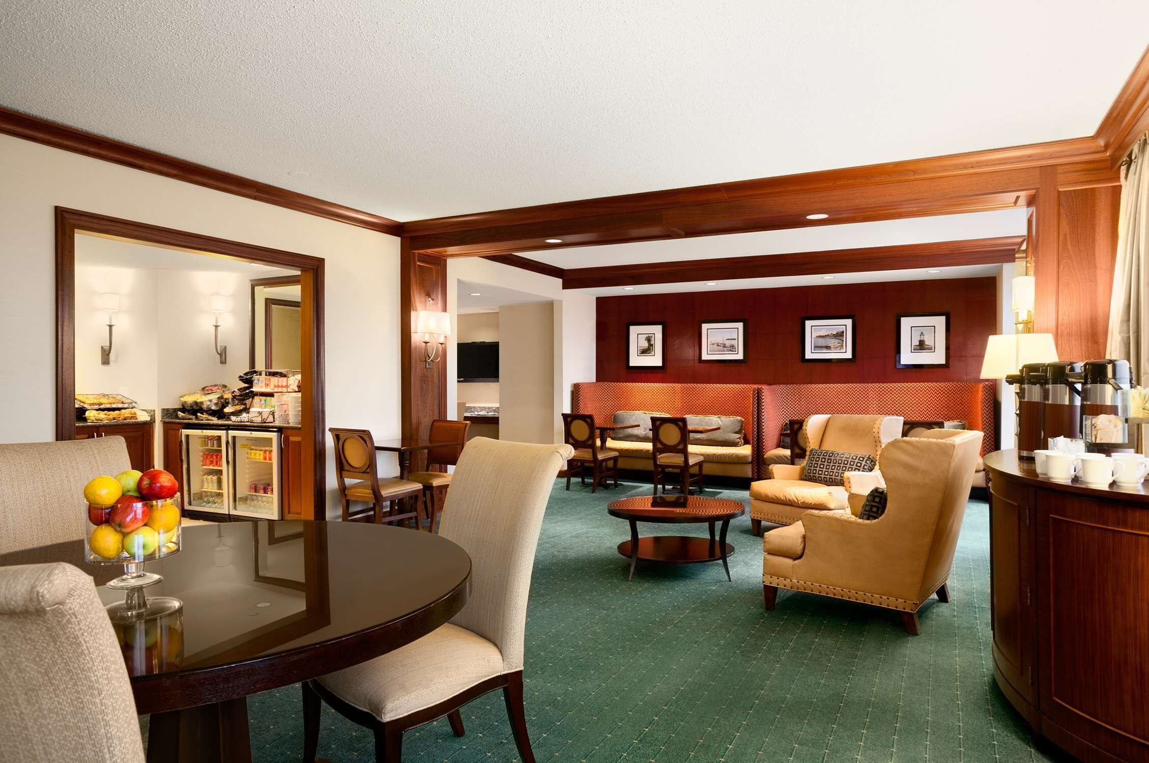 A hotel lobby with a dining area, seating, a refrigerator, and a television.
