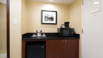 A compact kitchenette with a microwave, coffee maker, and a small refrigerator.