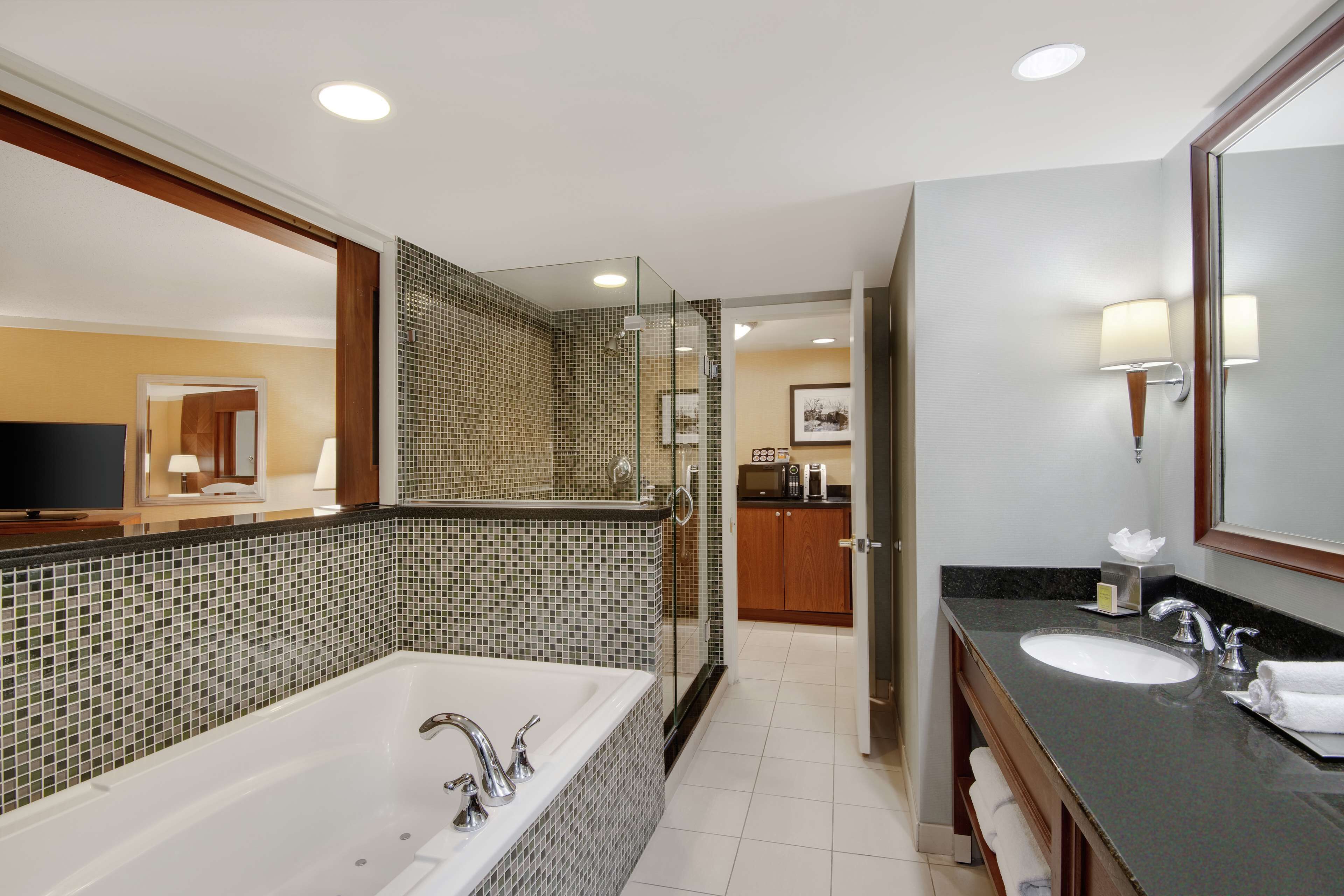 A modern bathroom with a large bathtub, a glass-enclosed shower, and a vanity with a sink and mirror.
