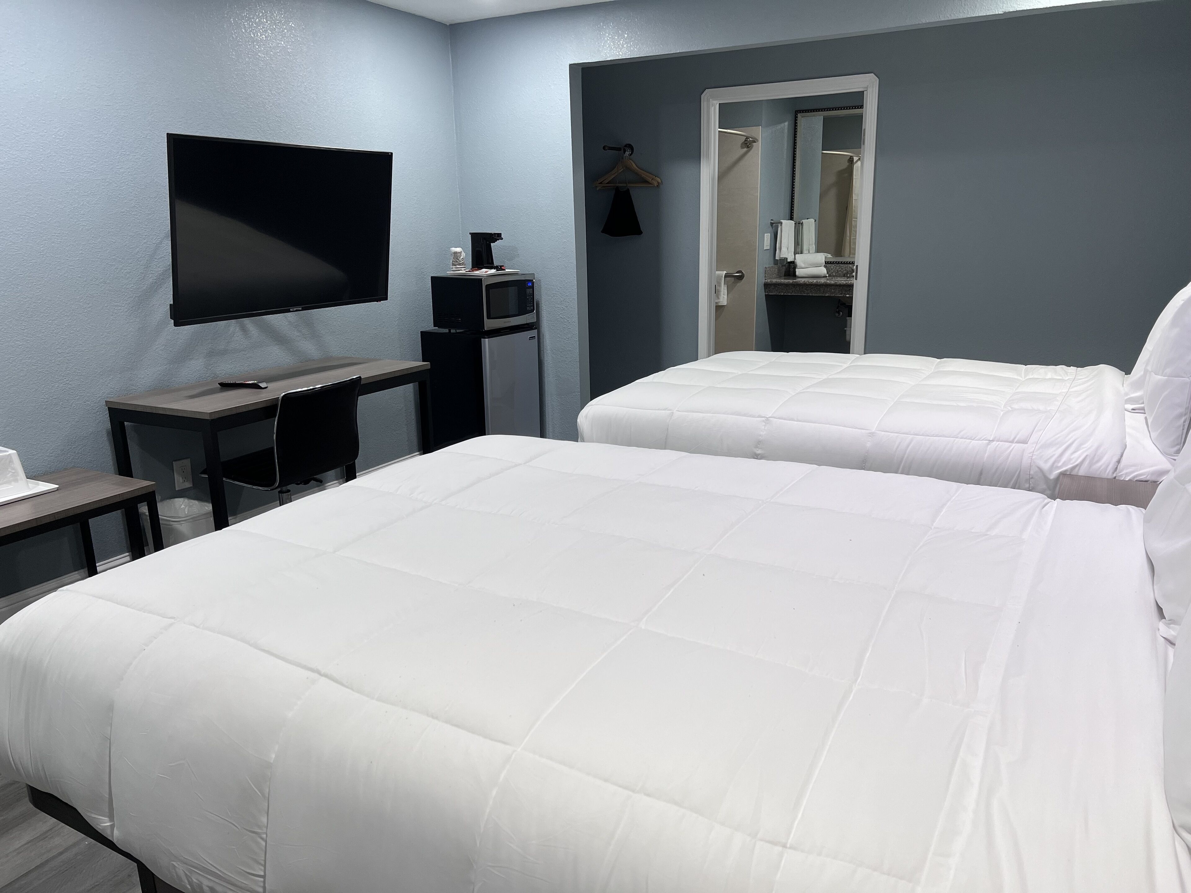 Een hotelkamer met twee bedden, een bureau met een televisie, een koffiezetapparaat en een spiegel.