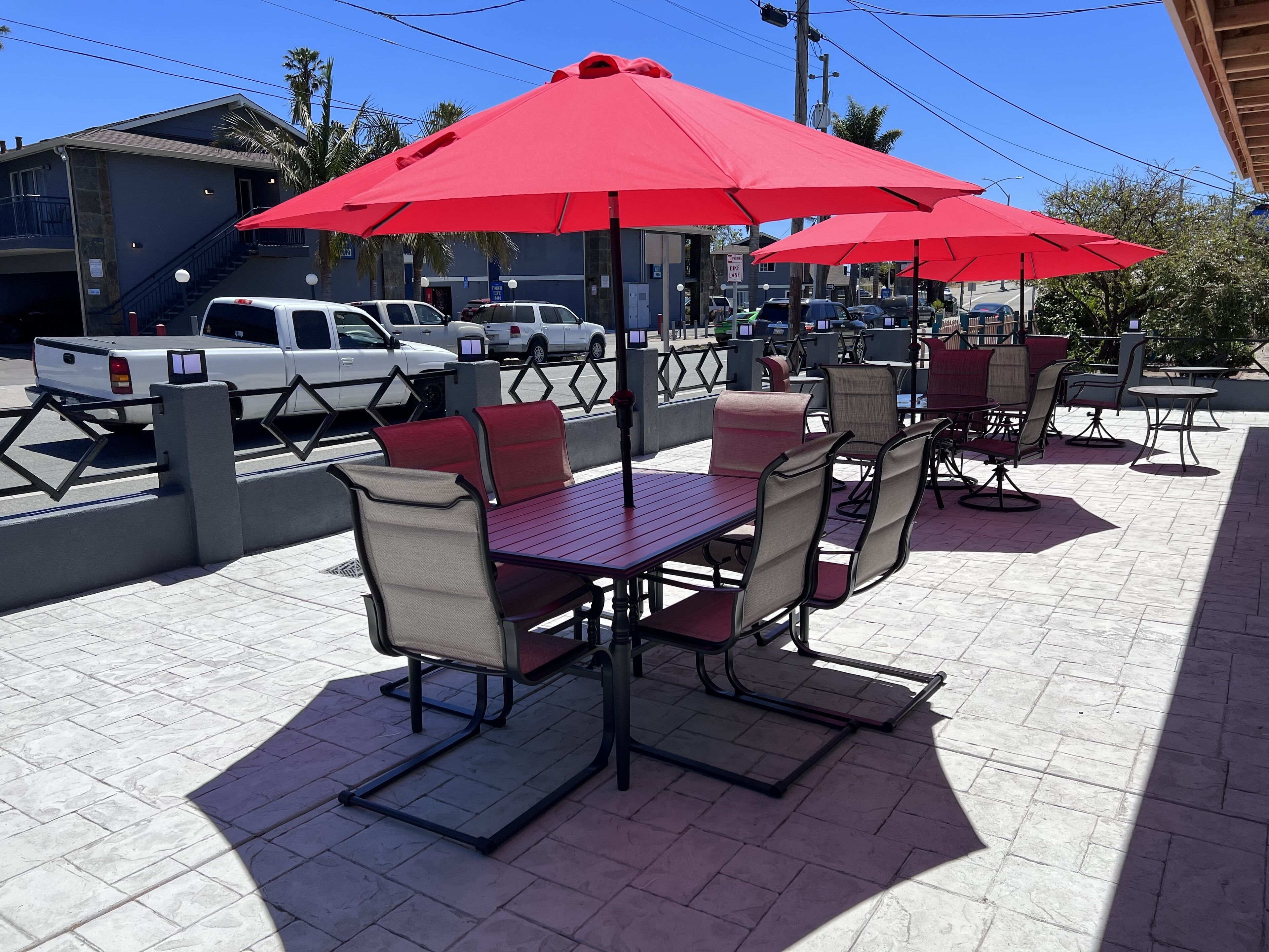 An outdoor patio with red umbrellas, tables, and chairs.