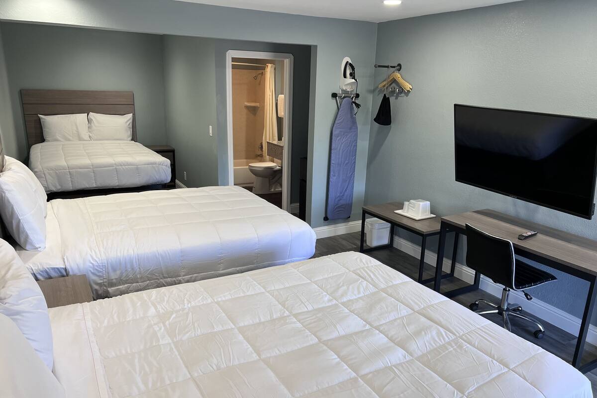 A hotel room with two queen beds, a TV, a desk, and a walk-in closet.