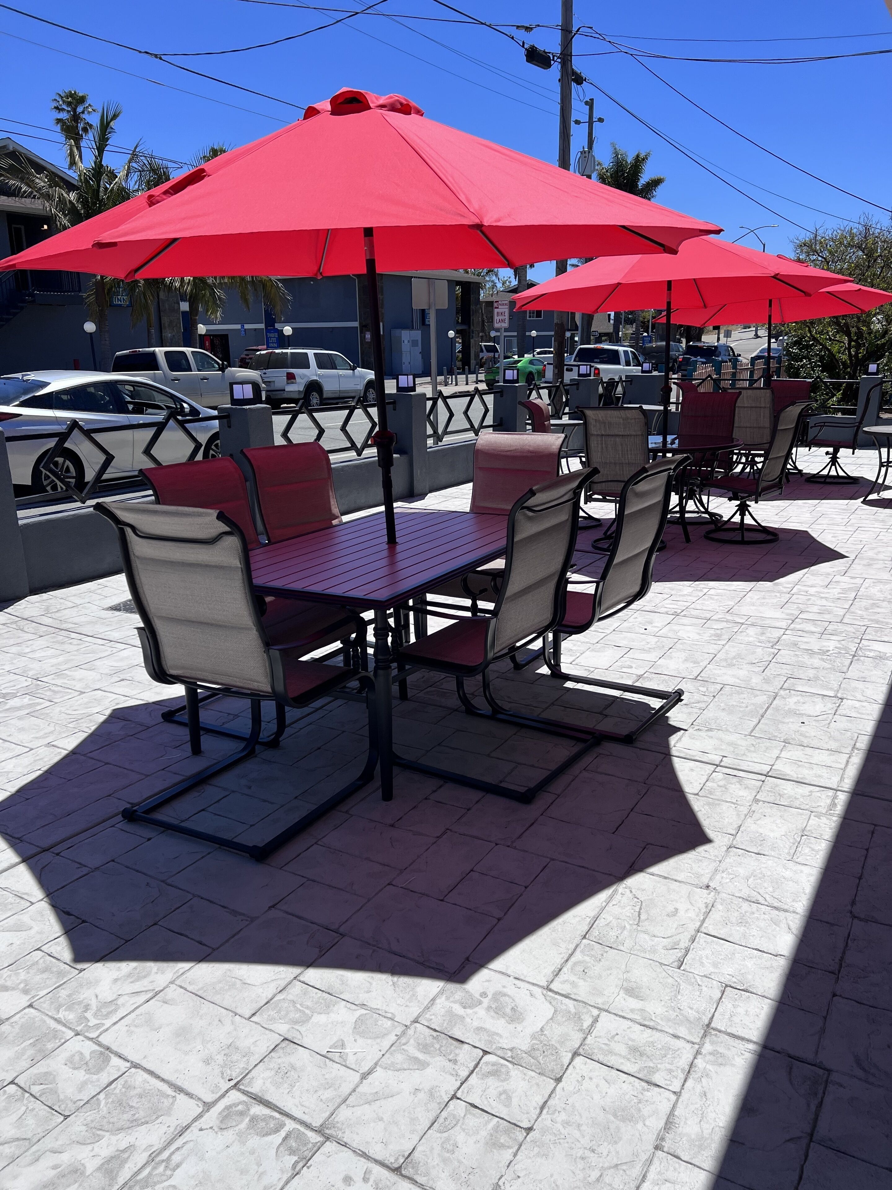 Outdoor patio seating with red umbrellas, arranged around tables and chairs.
