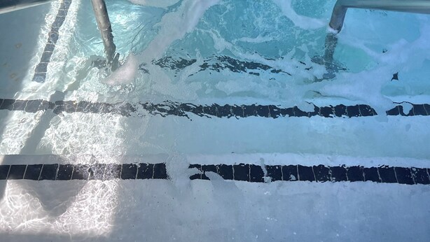 A rectangular swimming pool with clear water, marked lanes, and a metal ladder. - Surf City Inn and Suites (Santa Cruz)