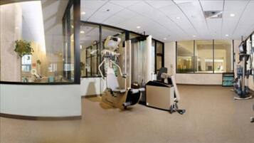 Eine geräumige Lobby mit einer großen Glaswand, einem Empfangsschalter und einem Laufband.