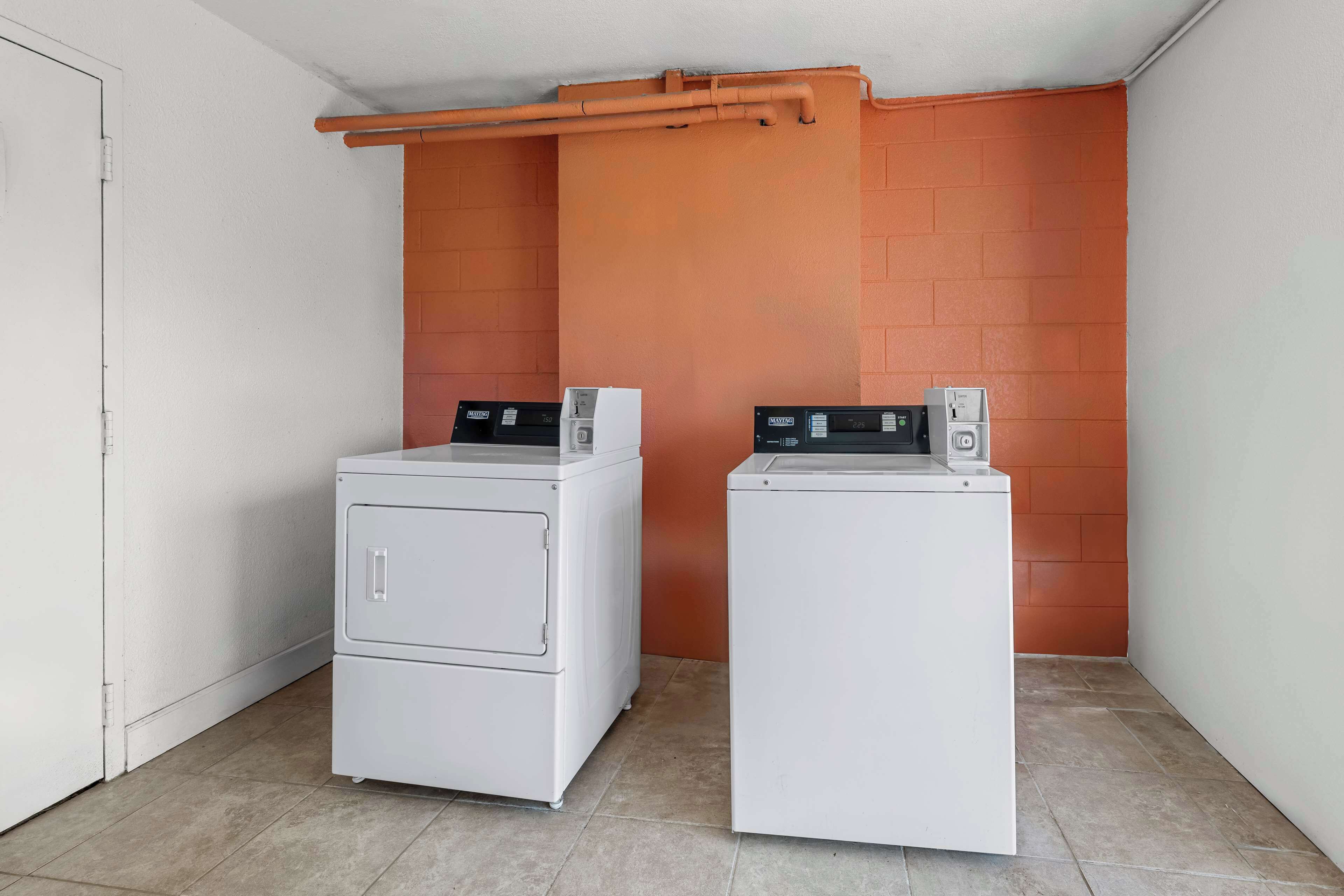 A laundry room with two white front-loading washing machines and a metal drying rack.
