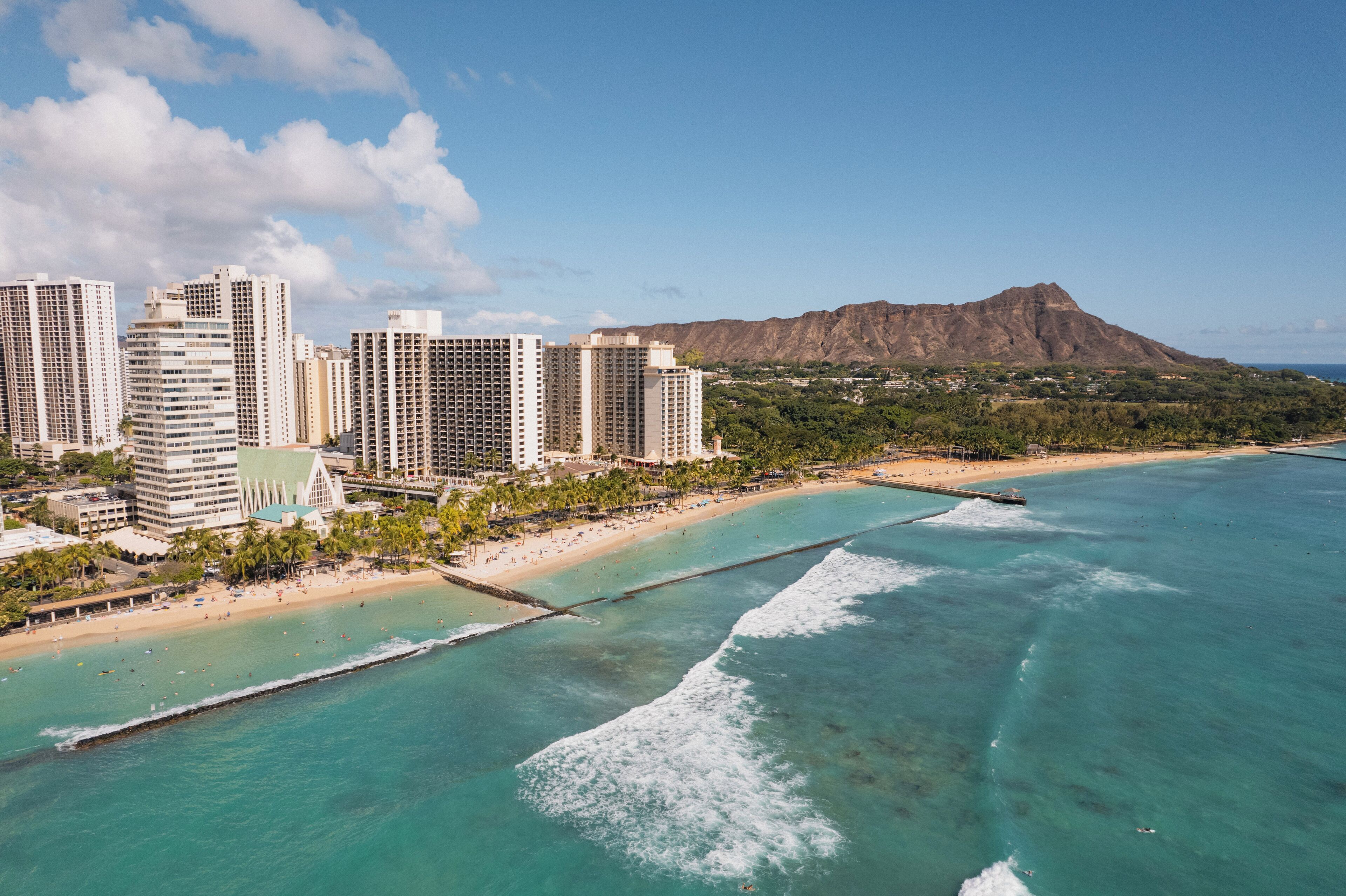 A coastal cityscape with high-rise buildings, a beach, and a mountain in the background.