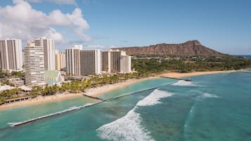 A coastal cityscape with high-rise buildings, a beach, and a mountain in the background.