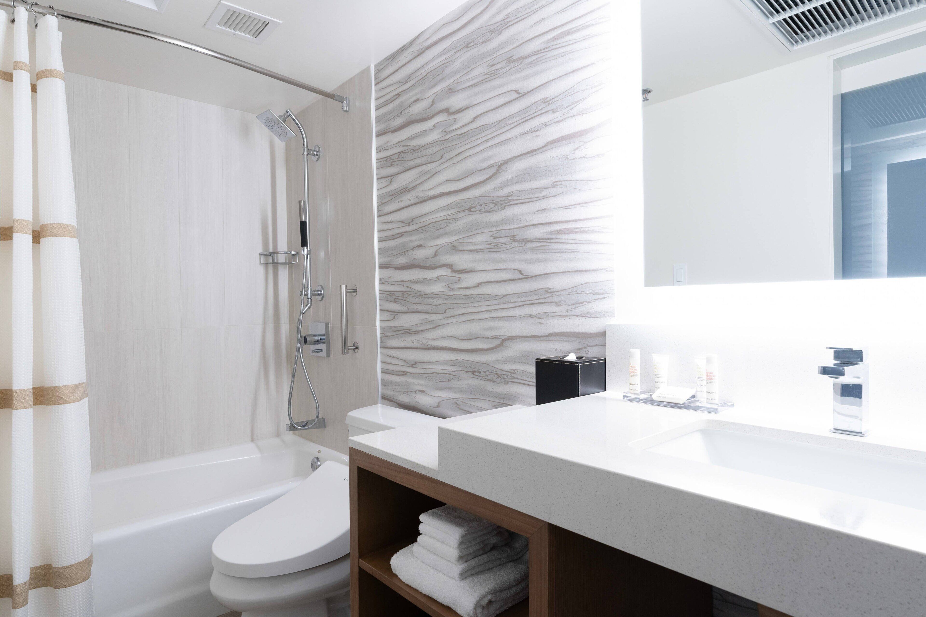 A modern bathroom with a shower, toilet, and sink.