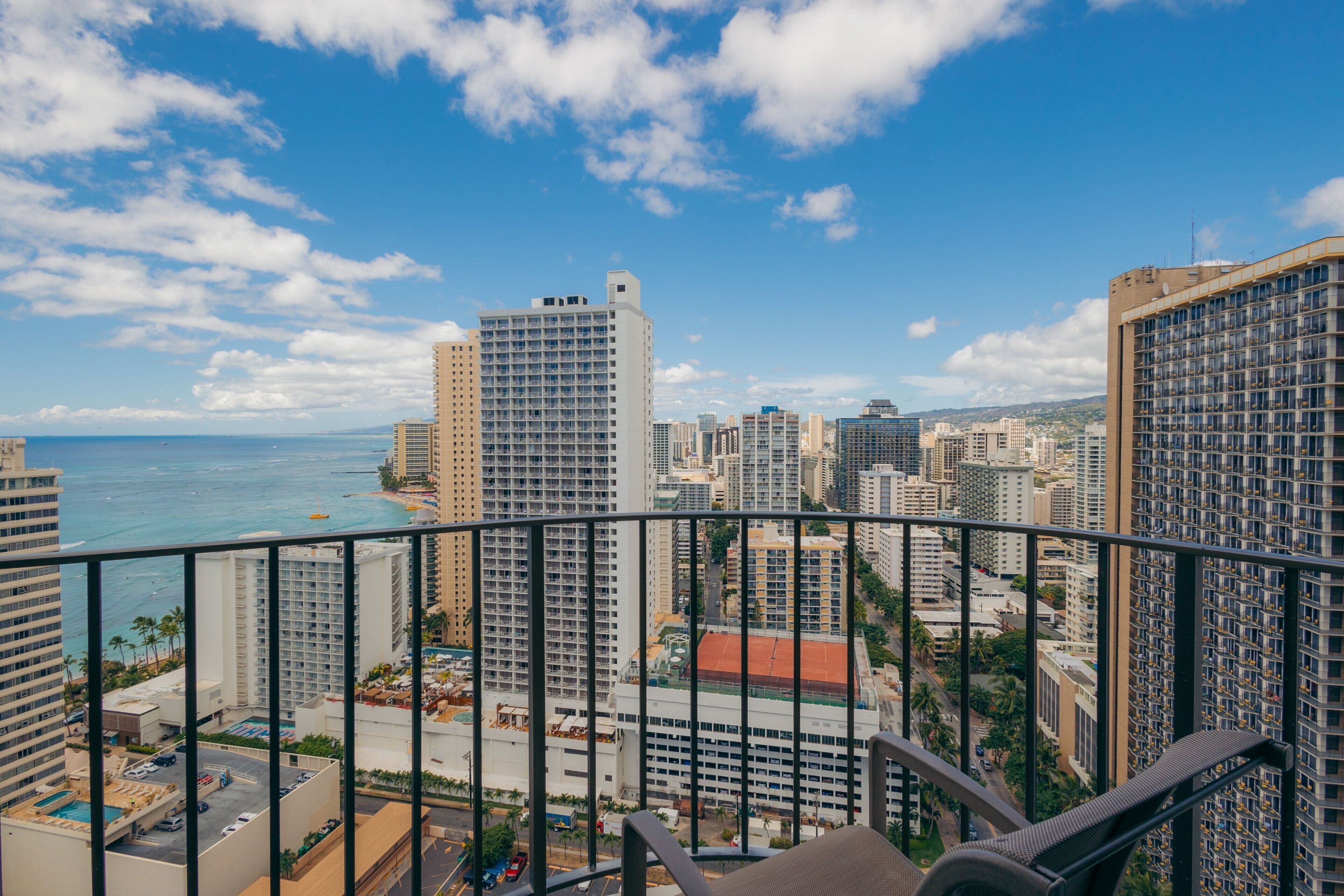 A high-rise hotel with a balcony overlooking a cityscape and the ocean.