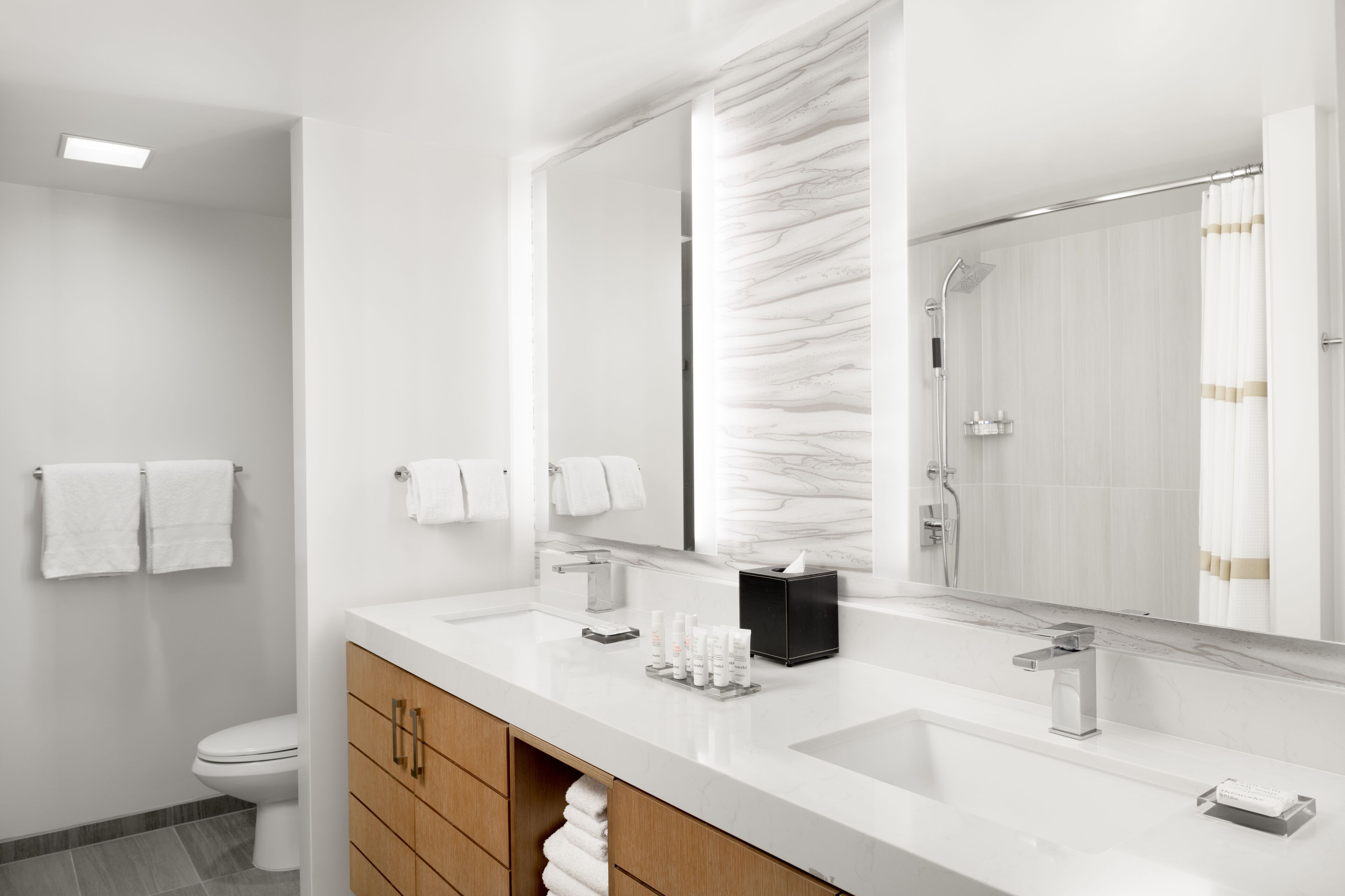 Un bagno moderno con uno specchio grande, due lavabi e una doccia.