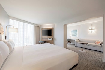 A hotel room with a large window overlooking a beach with palm trees and the ocean. at Waikiki Beach Marriott Resort & Spa