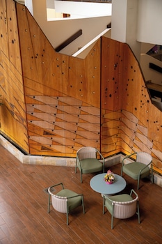 A modern hotel room with a flat-screen TV mounted on a wooden panel, a sofa, a small table, a chair, and a cabinet with drawers. at Waikiki Beach Marriott Resort & Spa