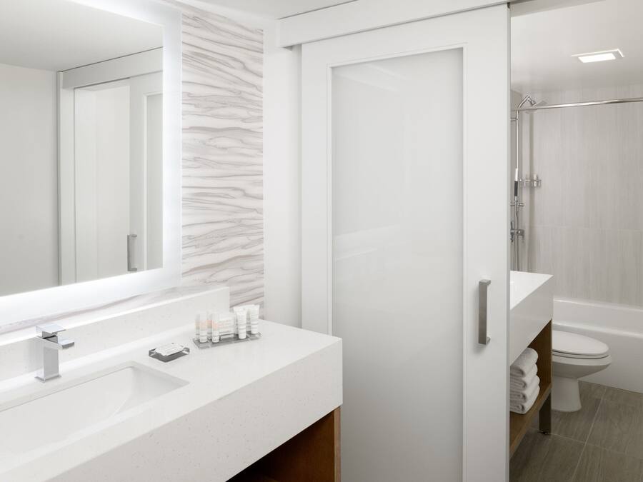 A modern bathroom with a white vanity, a large mirror, and a shower area.