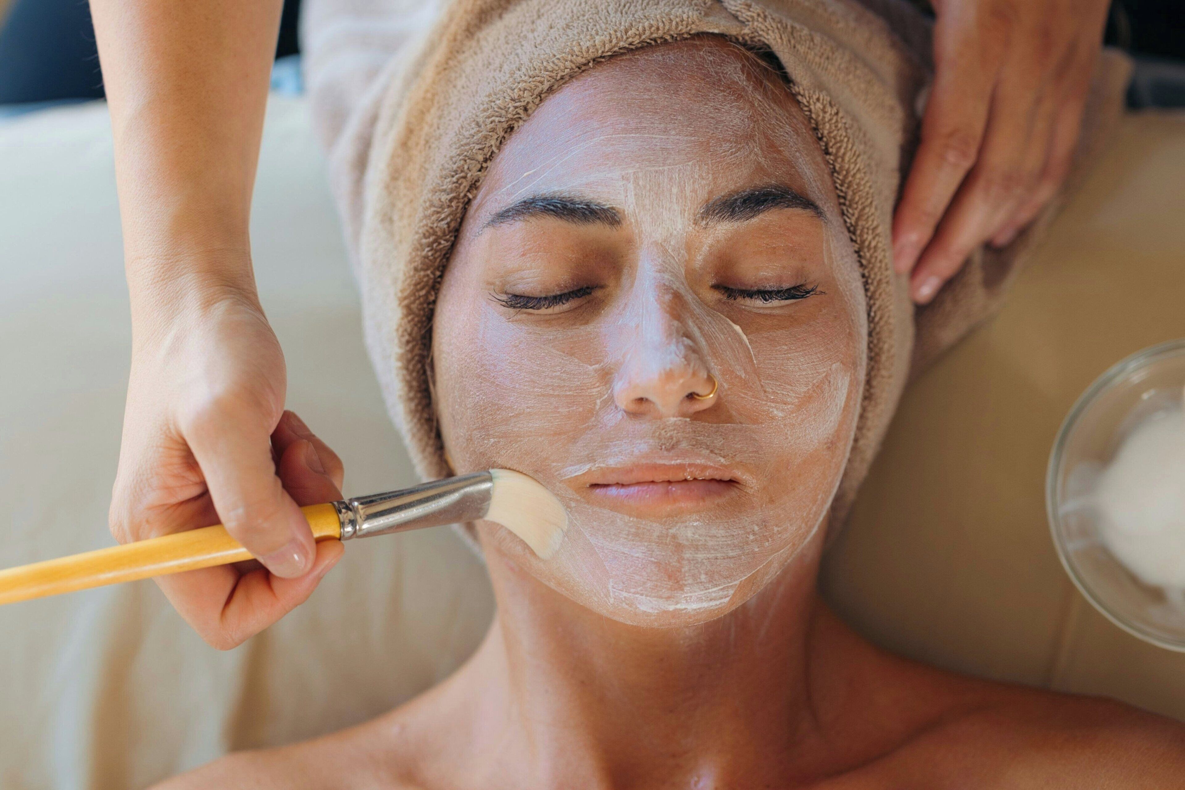 A person receiving a facial treatment with a brush.