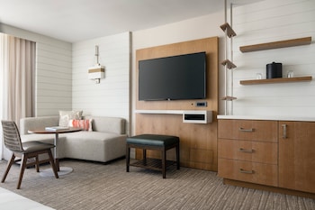 A hotel room with a large bed, a desk, a sofa, a television, and a window with curtains. at Waikiki Beach Marriott Resort & Spa