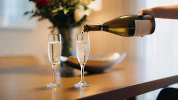 A bottle of wine being poured into two glasses on a table.
