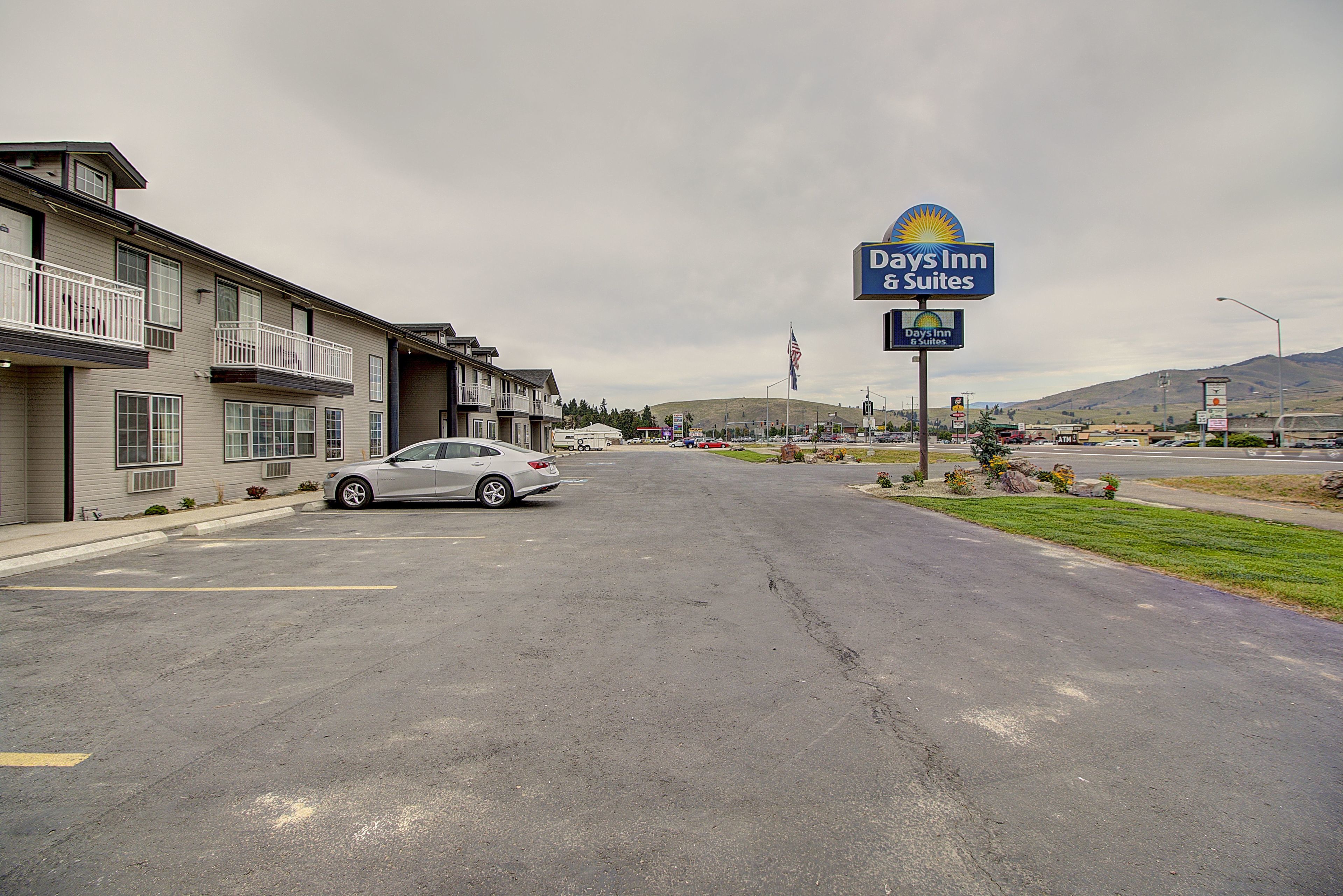 Un hôtel Days Inn & Suites doté d’un parking et d’une voiture garée devant l’entrée.