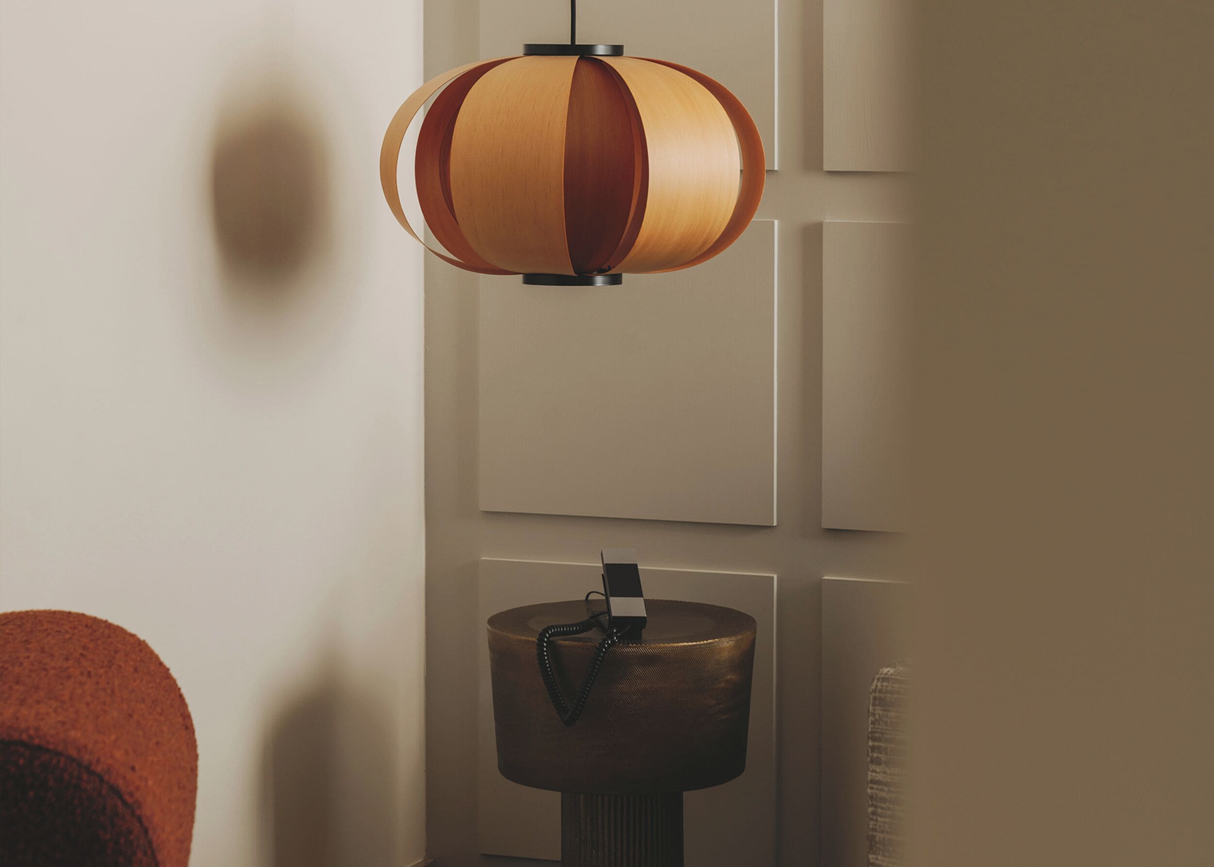 A modern room with a wooden pendant lamp and a round table.