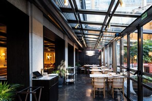 Un restaurant amb sostre de vidre, taules, cadires i plantes en testos.