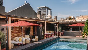 Zona de piscina en la azotea con asientos al aire libre y un bar.