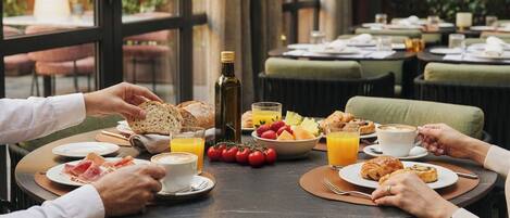 A breakfast setting with a table set for four, including croissants, fruit, and coffee.