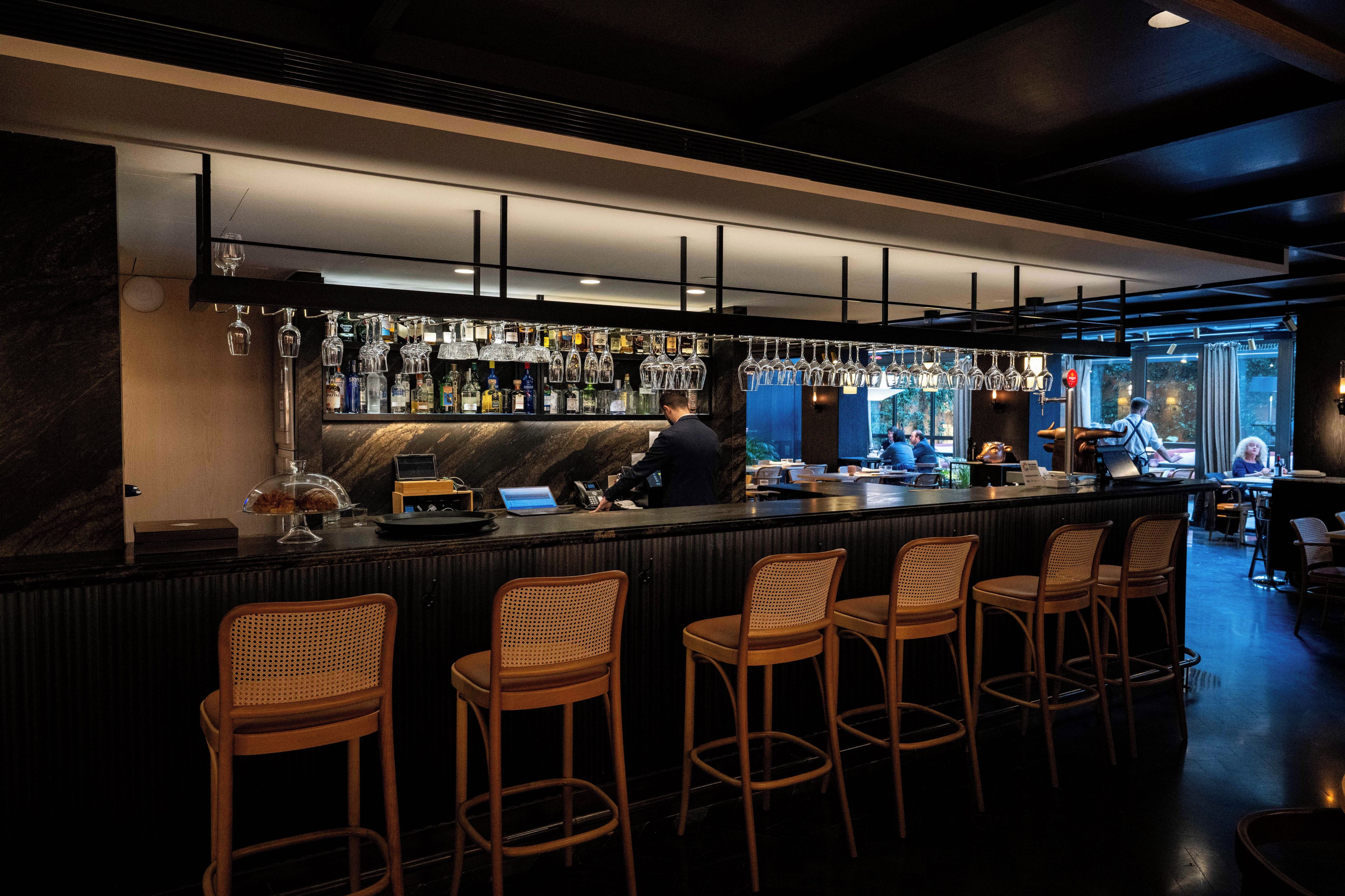 A bar area with a counter, bar stools, and a bartender.