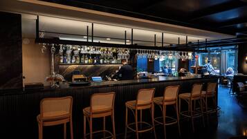 A bar area with a counter, bar stools, and a bartender.