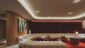 Una sala de estar moderna con un sofá curvo seccional, una mesa de centro de madera y una alfombra roja.
