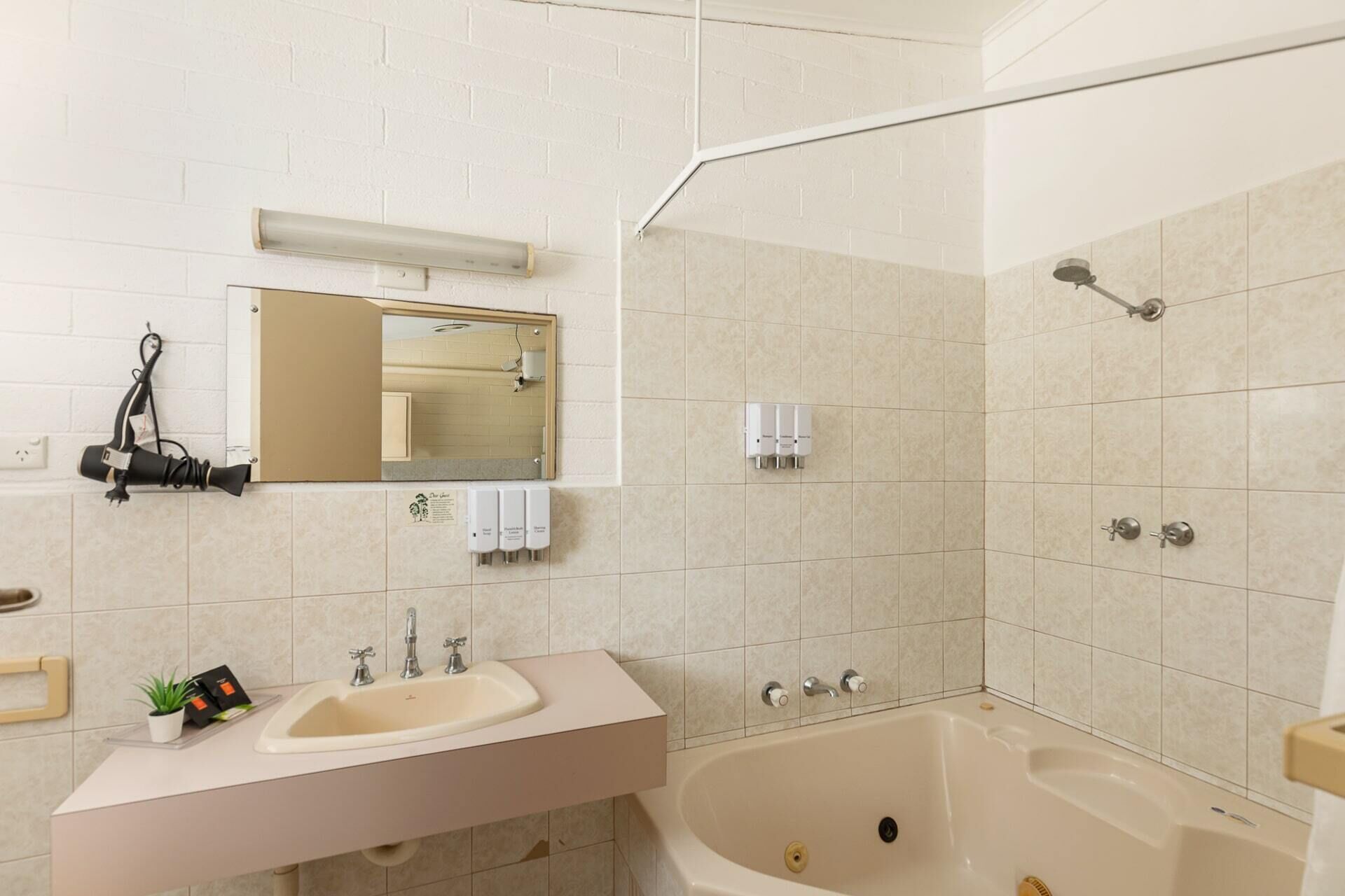 A modern bathroom with a sink, mirror, and bathtub.