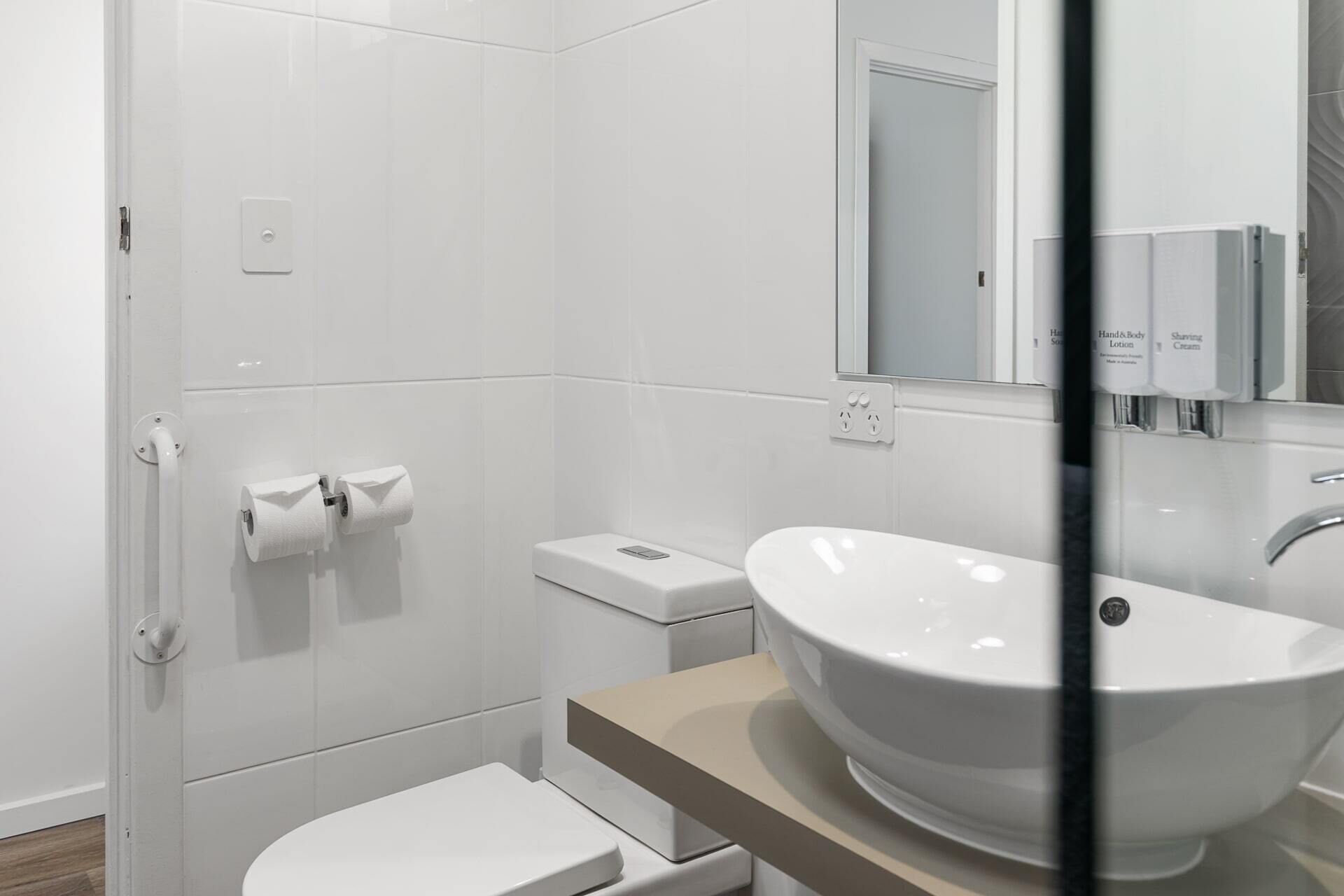 Et moderne badeværelse med hvid vask, toilet og bruseområde.