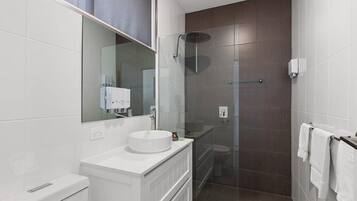 A modern bathroom with a white vanity, a glass shower enclosure, and a large mirror.