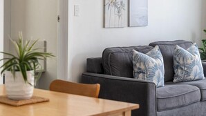 Un salón moderno con un sofá gris, una mesa de comedor de madera y una planta en maceta.