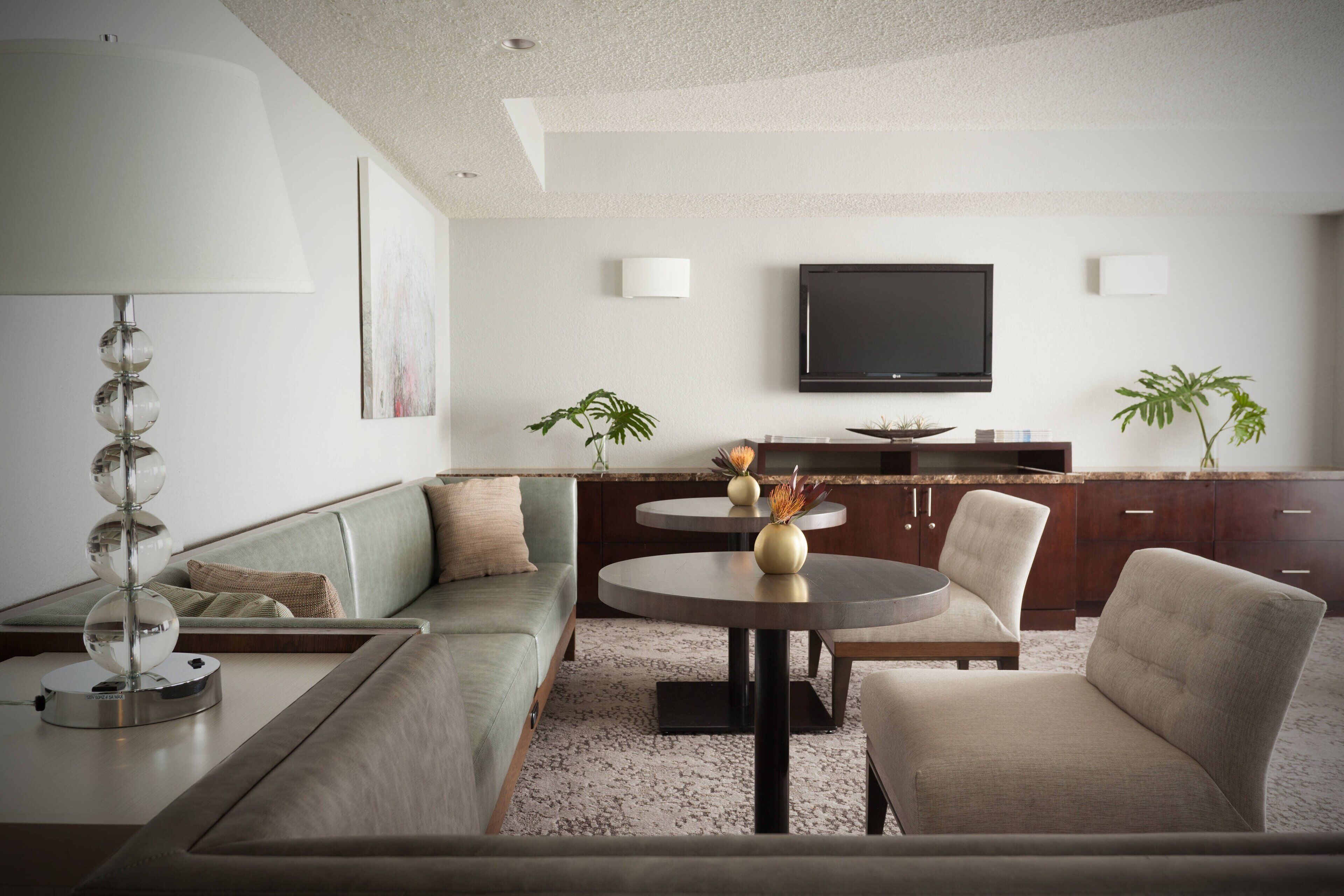 Una sala de estar moderna con un sofá, una mesa redonda y un televisor de pantalla plana montado en la pared.