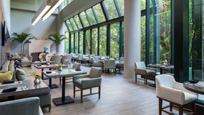 A spacious indoor area with multiple tables and chairs, large windows, and indoor plants. - Fort Lauderdale Marriott North (Fort Lauderdale)