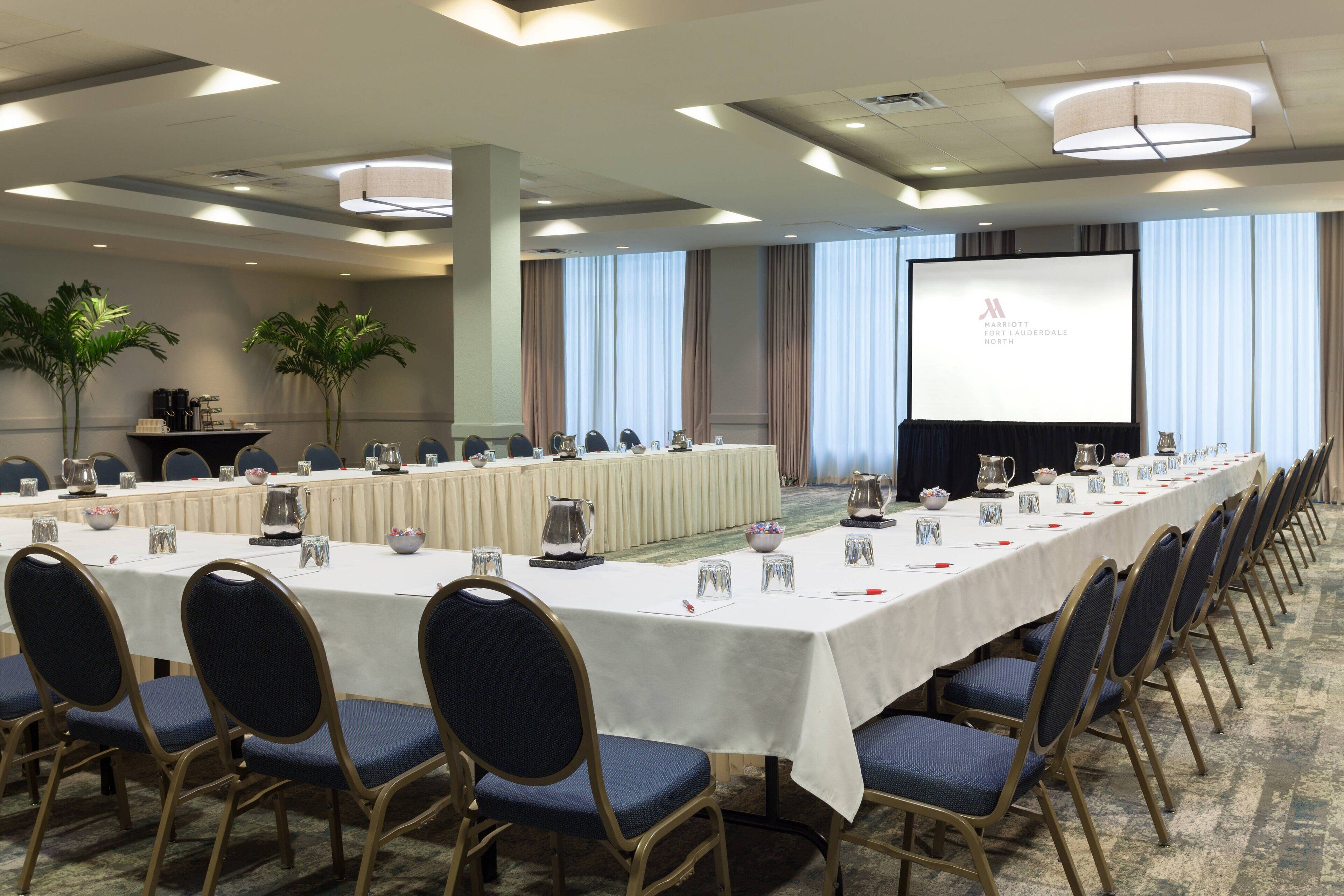 A conference room with a long table, chairs, and a projection screen.