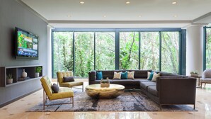 A modern living room with a large sectional sofa, a round coffee table, and a flat-screen TV mounted on the wall. - Fort Lauderdale Marriott North (Fort Lauderdale)
