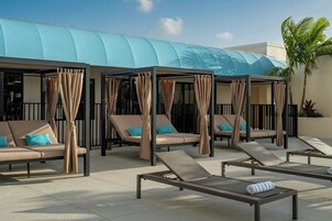 Un área de lounge en la azotea con tumbonas y una zona de estar cubierta, con un diseño arquitectónico moderno.