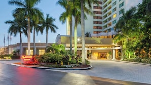 A Marriott North hotel entrance with palm trees, a landscaped garden, and a modern building facade.