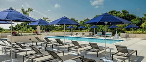 Una piscina al aire libre, sombrillas, sillones reclinables de piscina