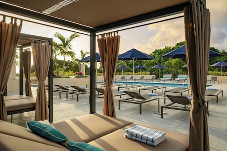 Una piscina al aire libre, sombrillas, sillones reclinables de piscina