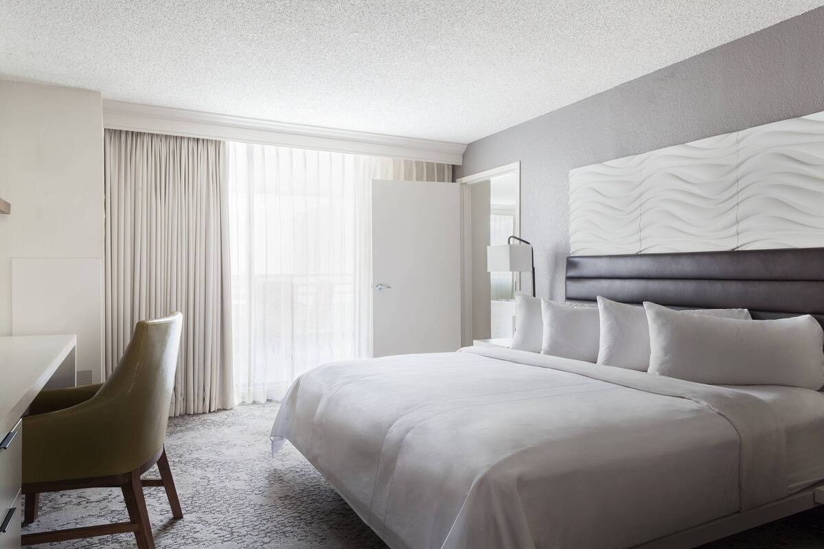 Ein modernes Hotelzimmer mit einem großen Bett, einem Schreibtisch und einem Sessel.