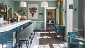 A bar area with a long counter, multiple stools, and a chandelier. There are chairs and a table in the adjacent seating area. - Richmond Hill Hotel (Richmond)