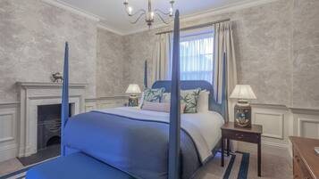 Quarto com cama de dossel, lareira e candelabro.