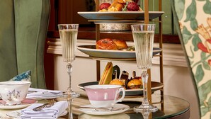 A table set for a tea service with a tiered stand holding pastries, a vase of flowers, and two glasses of water. - Richmond Hill Hotel (Richmond)