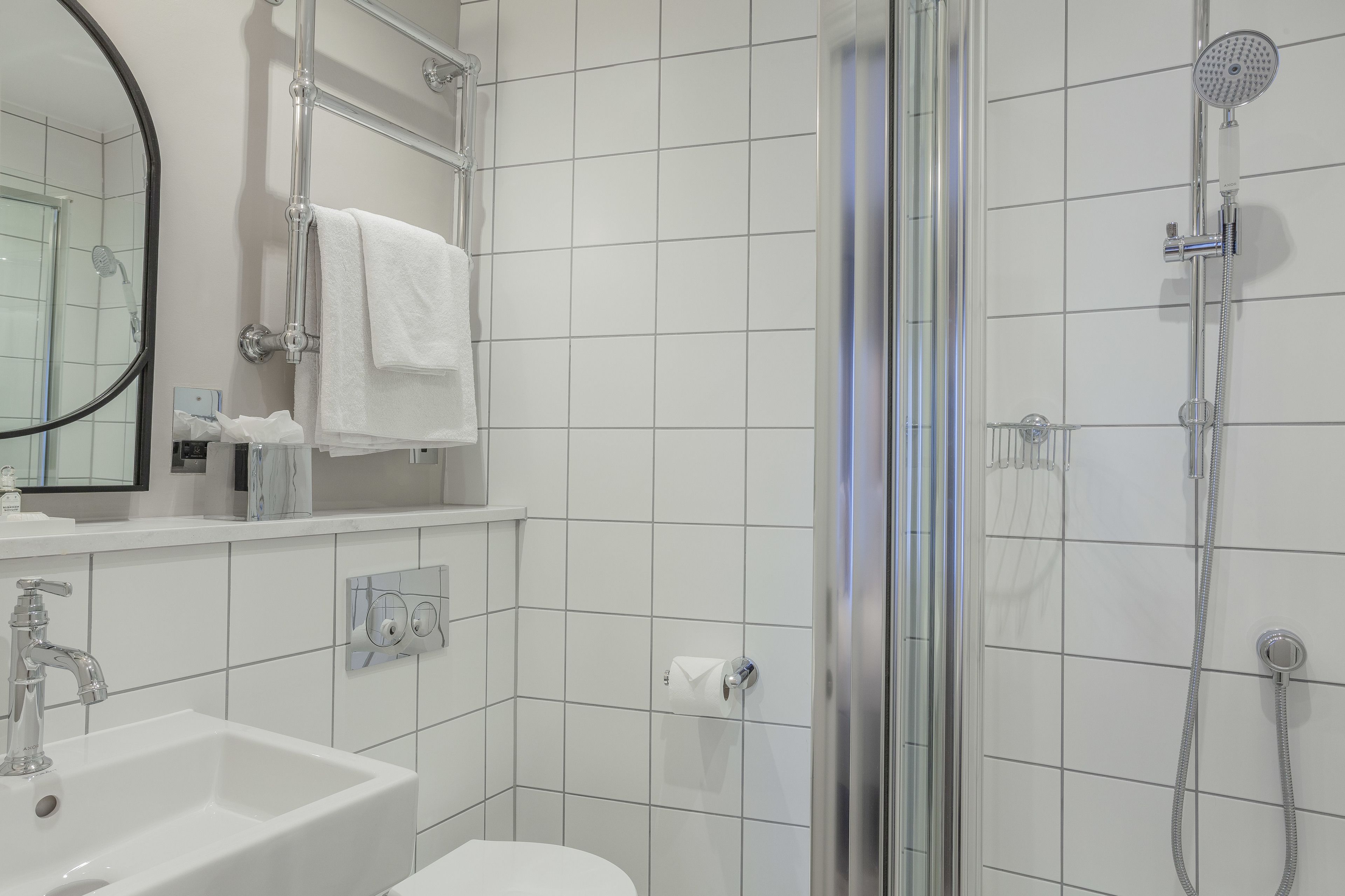 Une salle de bain moderne avec une douche à parois de verre, un lavabo blanc et un miroir.