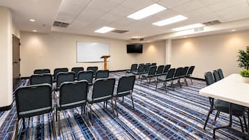 A conference room with a whiteboard, a TV, and a large table.
