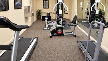 A gym with treadmills, weight machines, and a mirrored wall.
