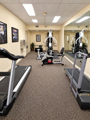 A gym with treadmills, weight machines, and a mirrored wall. - Gold Vault Inn (Radcliff)